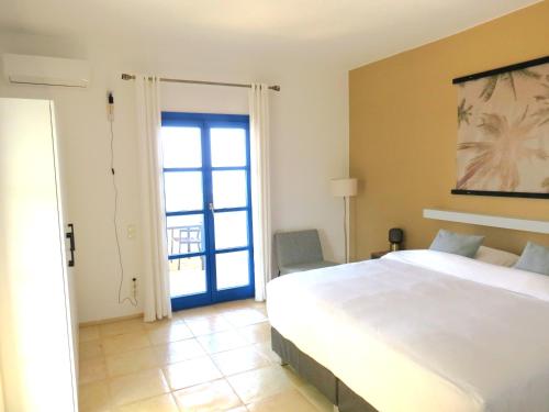 Un dormitorio con una gran cama blanca y una ventana en MERÁKI VILLA & APARTMENTS en Vamos