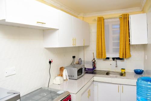 a kitchen with white cabinets and a microwave at The Hideout Thika Town in Thika