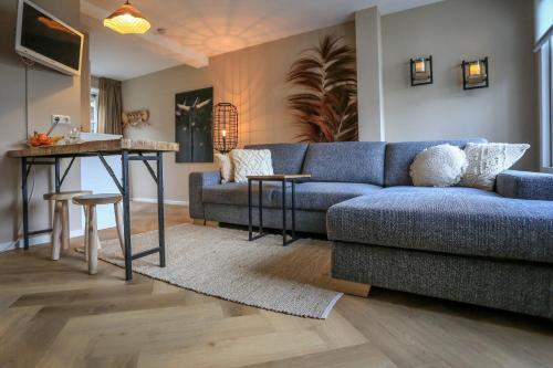 a living room with a blue couch and a table at De Kroft Beach Residences Noordwijk aan Zee in Noordwijk