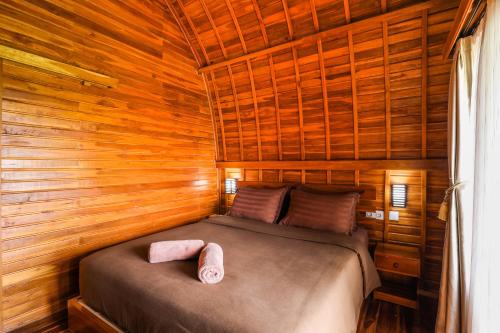 een slaapkamer met een bed in een houten hut bij The Polumb Garden Bedugul in Tabanan