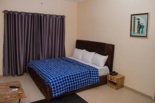 Schlafzimmer mit einem Bett mit einer blauen und weißen Bettdecke in der Unterkunft Go2Hotel45 in Lagos