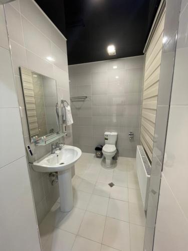 a white bathroom with a sink and a toilet at Chinor Hotel Fergana in Fergana