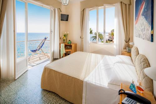 een slaapkamer met een bed en uitzicht op de oceaan bij Hotel Golfo e Palme in Diano Marina