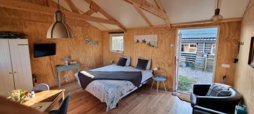 a bedroom with a bed in a room with wooden walls at B&B ZusenZomer in Oostwoud