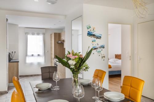 une salle à manger avec une table avec un vase de fleurs dans l'établissement Le Sunset Malouin, à Saint-Malo