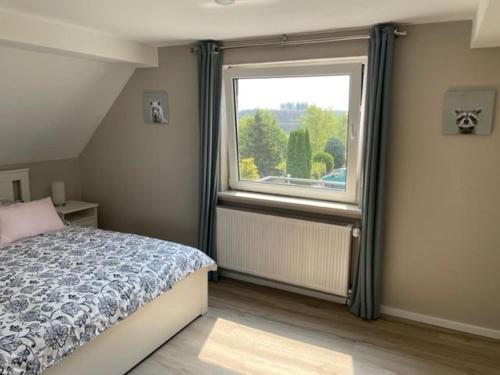 1 dormitorio con cama y ventana grande en Ferienwohnung Eulennest en Drolshagen