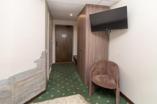 a hallway with a chair and a television on a wall at Hotel St. Barbara in Tallinn