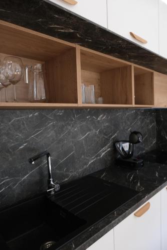 a kitchen with a black counter top with a sink at Apartments Emona FREE Parking-sauna-gym in Ljubljana