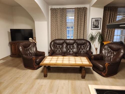 a living room with a leather couch and a coffee table at Penzion Rafaella in Česká Kamenice