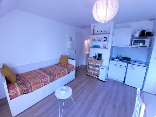 una piccola camera da letto con un letto e una cucina di LE NID DE BATZ SUR MER-Studio-Les Gîtes de la Côte d'Amour a Batz-sur-Mer