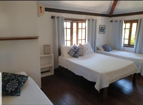 1 dormitorio con 2 camas y 2 ventanas en Vila Bahia casa 3, en Porto Seguro