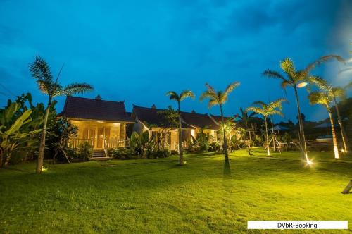 a house with palm trees in front of a yard at Dayung Villas By Reccoma in Nusa Lembongan