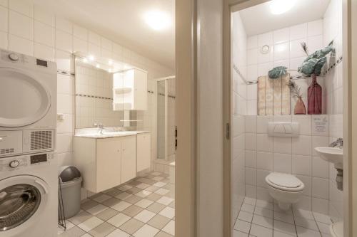 ein Badezimmer mit einer Waschmaschine und einem Waschbecken in der Unterkunft Wijde Blick appartement 210 Callantsoog in Callantsoog