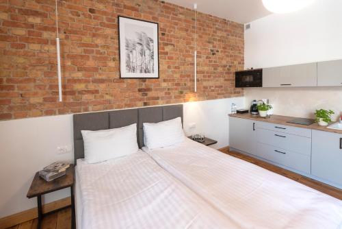 a large bed in a room with a brick wall at PROVENIR HOME KWIATOWA 5 in Poznań