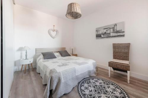 a white bedroom with a bed and a chair at Le Petit Colliourenc in Collioure