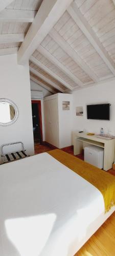 a bedroom with a large white bed and a desk at Guarda Rios in Vila Nova de Milfontes