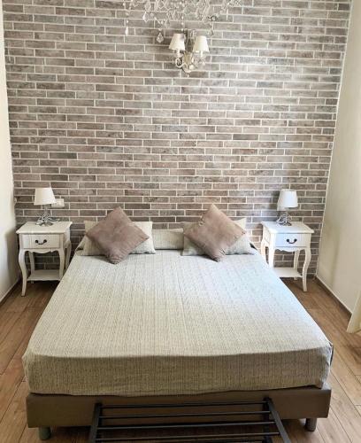 a bedroom with a brick wall and a bed with two tables at Maglo Centro in Bologna
