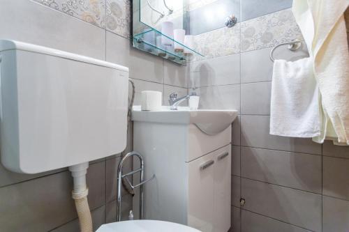 a bathroom with a white toilet and a sink at Rooms Marija in Malinska