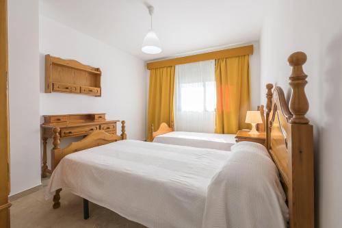 a bedroom with two beds and a dresser and a window at Boliches in Arcos de la Frontera