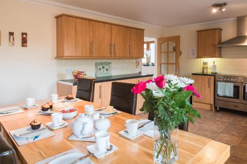 a kitchen with a wooden table with a vase of flowers at Keepers Lodge with Hot Tub in Forgandenny