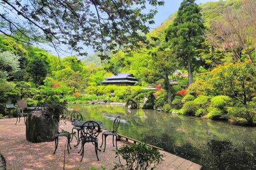 a park with benches and a river and a building at Yoshiike Ryokan in Hakone