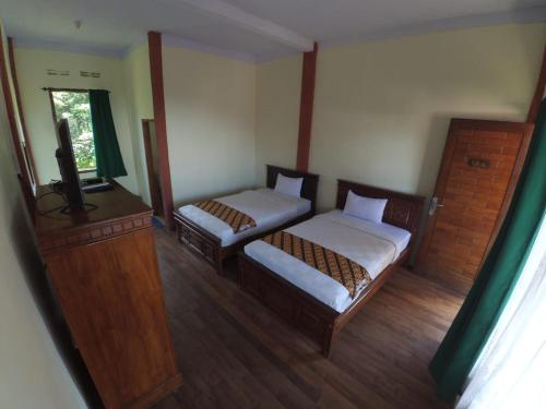 ein Schlafzimmer mit 2 Betten und einem TV in der Unterkunft Istana Petani in Lambangkuning