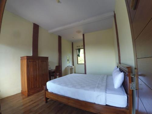 a bedroom with a white bed and a wooden cabinet at Istana Petani in Lambangkuning