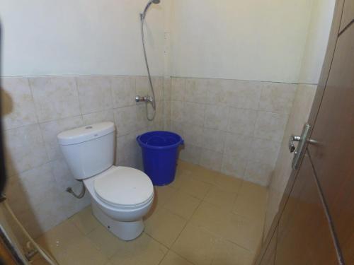 ein Badezimmer mit einem WC und einem blauen Mülleimer in der Unterkunft Istana Petani in Lambangkuning