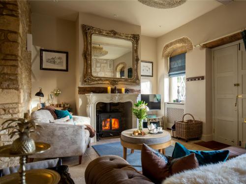 ein Wohnzimmer mit Kamin und Spiegel in der Unterkunft Pineapple Spa Cottage in Stow on the Wold