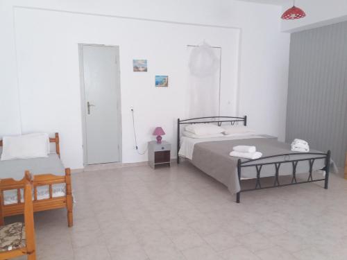 a bedroom with two beds and a table and a door at Studio George - near the beach in Matala