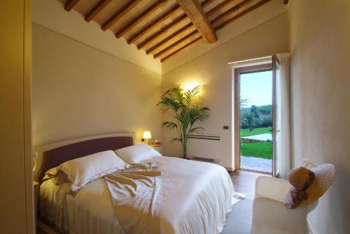 a bedroom with a bed and a window and a chair at Borgo Canalicchio Di Sopra Relais in Montalcino