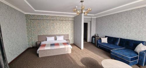 um quarto de hotel com uma cama e um sofá em Rooms Hotel Semey em Semey