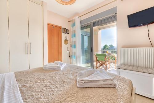 a bedroom with a bed with a tv and a balcony at Elegant new maisonette near the sea in Egina