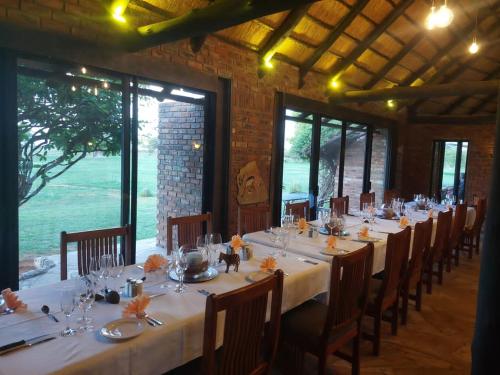 a long table with white tables and chairs in a room at Fiume Lodge CC in Groutfontein