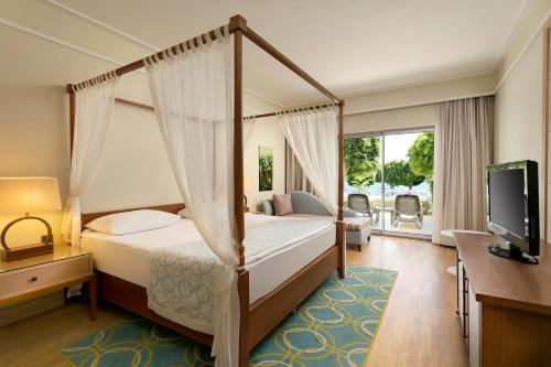 a bedroom with a canopy bed and a television at Xanadu Island in Akyarlar