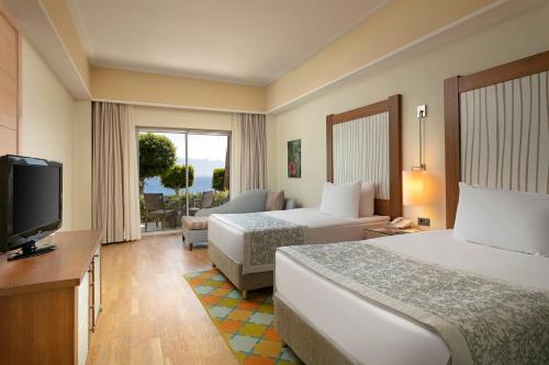 a hotel room with two beds and a television at Xanadu Island in Akyarlar