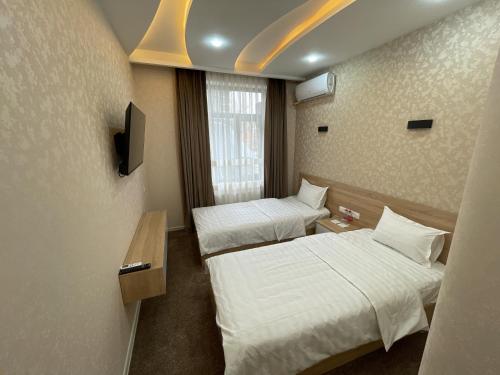 a hotel room with two beds and a tv at Chinor Hotel Fergana in Fergana