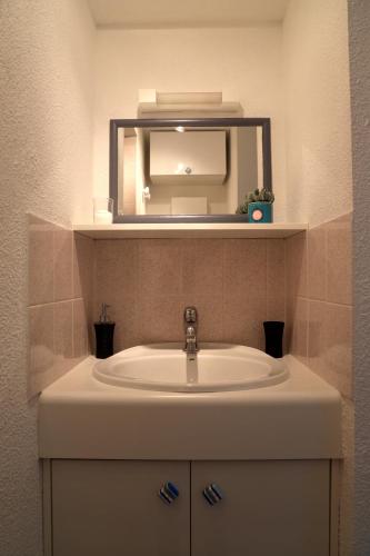 une salle de bain avec un lavabo et un miroir dans l'établissement Le Clapotis - T2 à 100 m de la plage avec parking, à Sarzeau