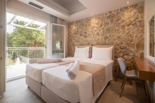 two beds in a bedroom with a stone wall at Villa Coral in Potamós