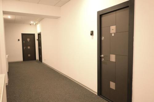 un pasillo vacío con puertas negras y alfombra en Luana Airport Apartments #4, en Otopeni