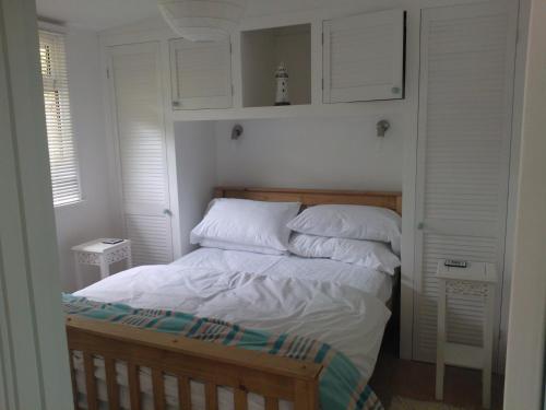 a bedroom with a bed with white sheets and pillows at Whiteshell Chalets in The Mumbles