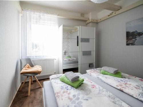 a bedroom with two beds and a chair and a window at Ferienwohnung Bär in Großräschen