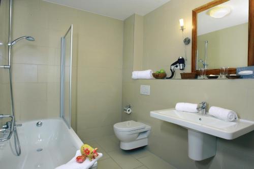 a bathroom with a sink and a toilet and a mirror at Ampervilla Hotel in Fahrenzhausen