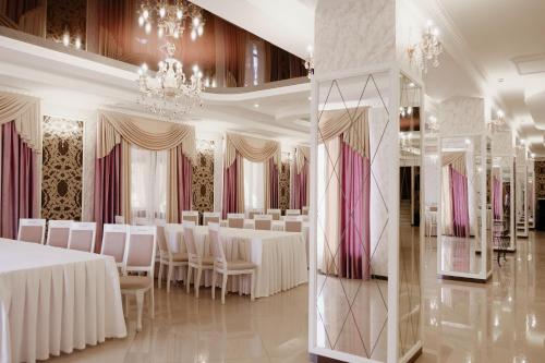 une salle de banquet avec des tables et des chaises blanches ainsi qu'un lustre dans l'établissement Готель Хутір, à Malyye Khutora