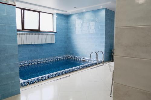 baño con bañera grande con azulejos azules en Готель Хутір, en Malyye Khutora