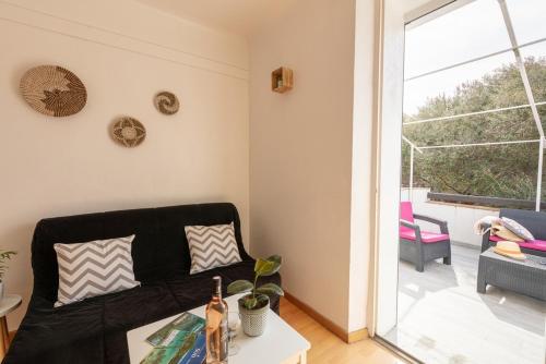 a living room with a black couch and a window at La Maison de Papou, charmante maison de village avec vue mer idéalement située à la Madrague in Hyères