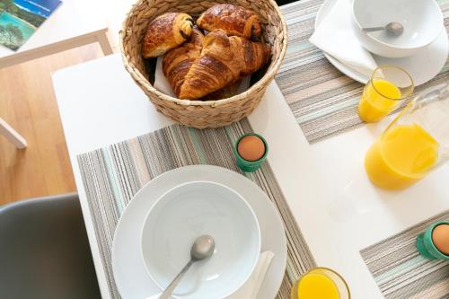 a table with a basket of bread and orange juice at La Maison de Papou, charmante maison de village avec vue mer idéalement située à la Madrague in Hyères