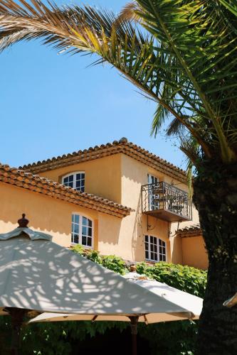 a building with an umbrella and a palm tree at Hôtel Villa Marie Saint Tropez in Saint-Tropez