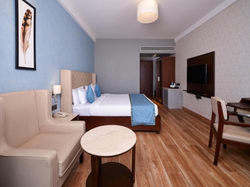 a hotel room with a bed and a couch and a table at Enrise By Sayaji Rau Indore in Indore
