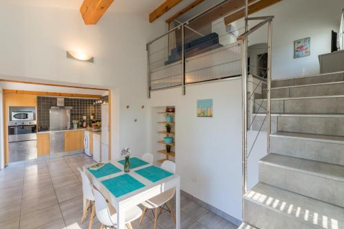 une cuisine et une salle à manger avec une table et un escalier dans l'établissement La Bastide, villa en duplex idéalement située à quelques pas de la mer, à Hyères
